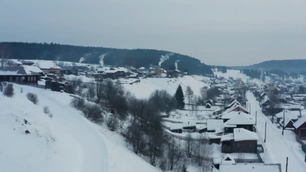 Widok z powietrza na dym wydobywający się z pieców w drewnianych domach w wiosce zimą — Wideo stockowe