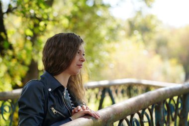 Demir köprünün üzerinde duran güzel genç bir kadının portresi. Çekici bir kadın kırsal kesimde doğayı seyrediyor.