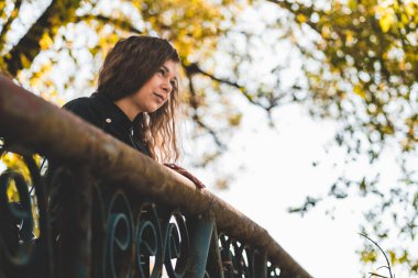 Demir köprünün üzerinde duran güzel genç bir kadının portresi. Çekici bir kadın kırsal kesimde doğayı seyrediyor.