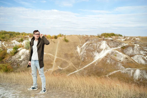 Mannen Med Glasögon Jeans Shirt Och Cape Står Kuperad Terräng — Stockfoto