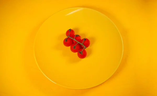 유기농 토마토를 접시와 배경에 얹는다 노란색 배경에 노란색 접시에 토마토입니다 — 스톡 사진