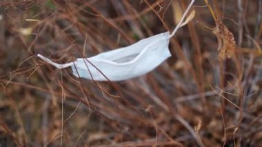 Tıbbi maskeyi kuru otlara yakın tut. Terk edilmiş tıbbi maske rüzgarda sallanıyor..