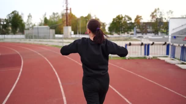 体育场的活跃女性 在体育场进行户外运动时 身穿运动服和防护面具的年轻女性适合在红道上跑步 — 图库视频影像