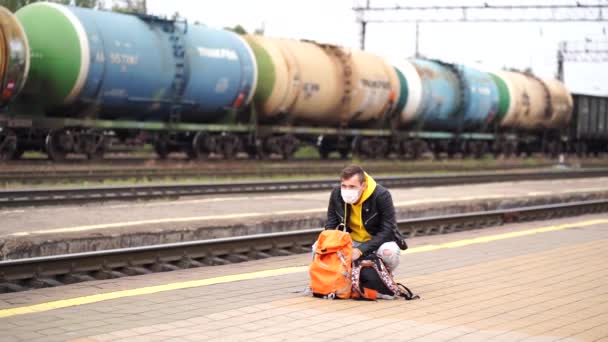 年轻人站在站台上等火车 在铁路站台上背着背包等待乘火车的男性乘客 旅行和娱乐的概念 — 图库视频影像