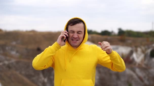 Tepe Arazisindeki Akıllı Telefondan Konuşan Kapüşonlu Yakışıklı Adamı Yakından Çek — Stok video