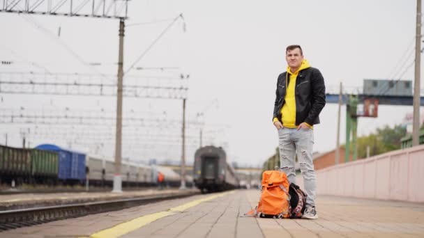 Młody Człowiek Stoi Peronie Czeka Pociąg Mężczyzna Plecakami Peronie Kolejowym — Wideo stockowe