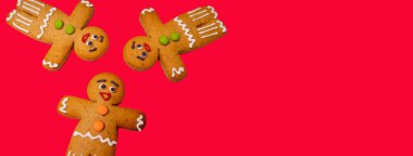 Kırmızı arka plandaki zencefilli çörekleri kapatın. Noel havası için süslü zencefilli çörekler ve metin için yer. Bayramda klasik kurabiye kavramı