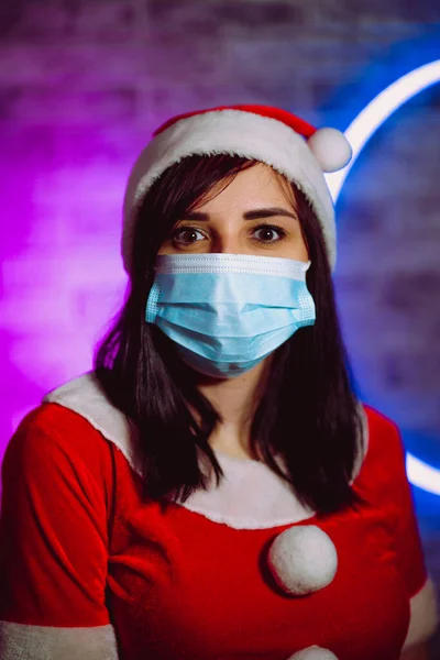 Молодая Женщина Медицинской Маске Костюм Санта Клауса Против Освещенной Стены — стоковое фото