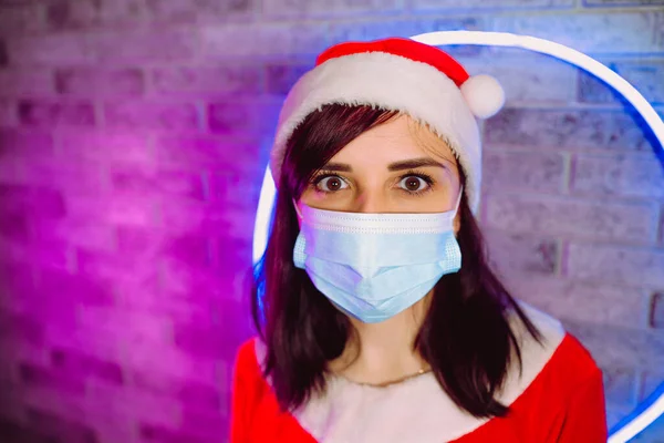 Giovane Donna Maschera Medica Vestito Babbo Natale Contro Parete Illuminata — Foto Stock