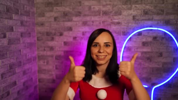 サンタクロースの若い女性は 照明の壁の背景にスーツ クリスマスのお祝いの概念 — ストック動画