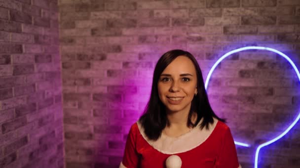 サンタクロースの若い女性は 照明の壁の背景にスーツ クリスマスのお祝いの概念 — ストック動画
