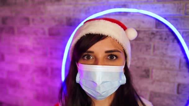 Wanita Muda Bertopeng Medis Dan Setelan Santa Claus Menghadap Dinding — Stok Video