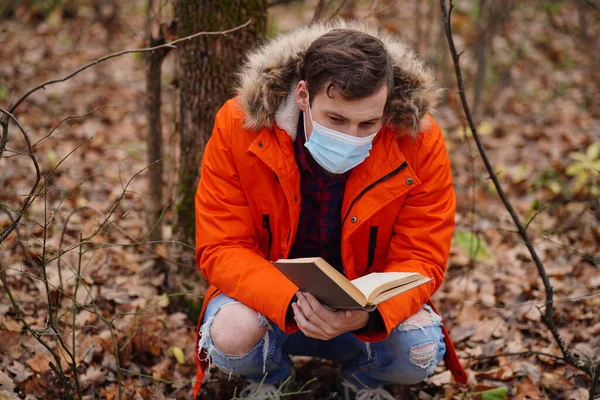 Взрослый Мужчина Медицинской Маске Приседает Земле Читает Книгу Осеннем Лесу — стоковое фото