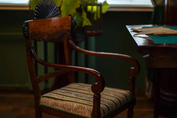 Close up of chair and desk in room. Writing table with old notebook and white feather indoors