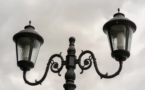Close up of street lamp on background of gray sky. Old street light in cloudy weather