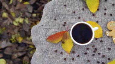 Tatlı zencefilli çörek adam ve koyu espresso kahvesi renkli sonbahar yapraklarının yanına parktaki keten kumaşın üzerine yerleştirilmiş..