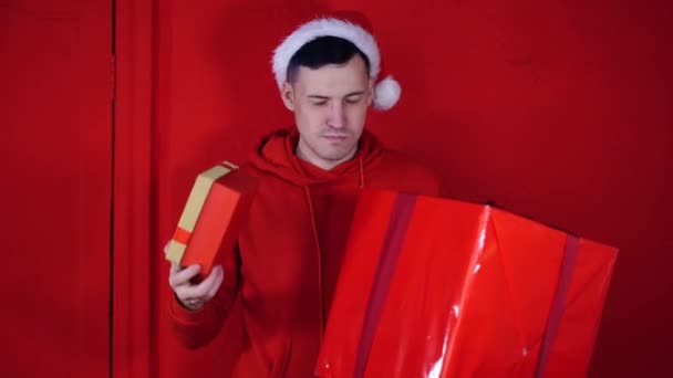 Young Handsome Man Santa Claus Hat Chooses Small Large Gift — Stock Video