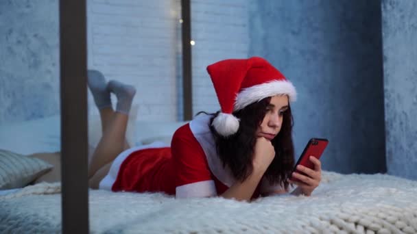 Mujer Joven Traje Santa Claus Navega Teléfono Inteligente Acostado Cama — Vídeos de Stock