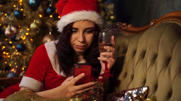 Young Woman Santa Claus Suit Glass Champagne Browses Smartphone Sitting — Stock Video