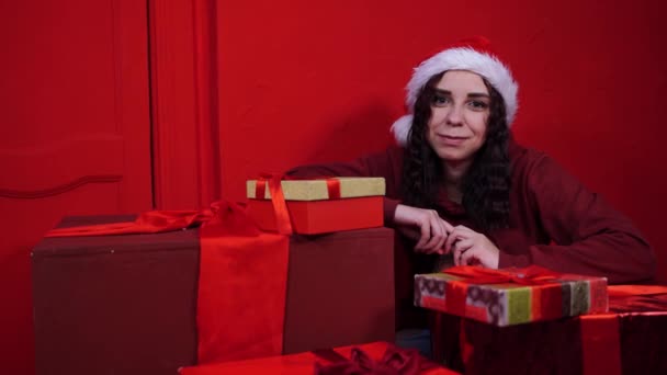 Jovem Mulher Chapéu Papai Noel Sentado Presentes Perto Parede Vermelha — Vídeo de Stock