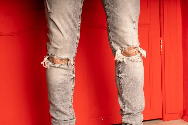 Close Men Legs Jeans Holes Red Background Fashionable Holes Grey — Stock Photo, Image