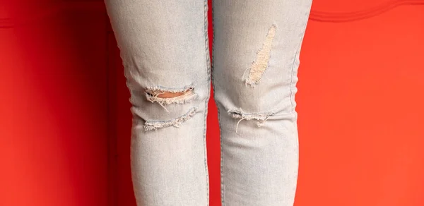 Detailní Záběr Ženské Nohy Džínách Otvory Červeném Pozadí Módní Díry — Stock fotografie