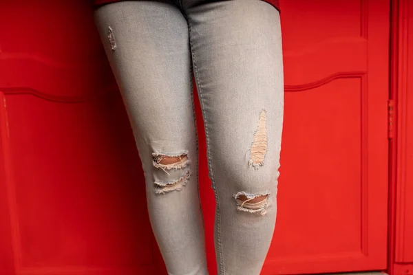 Nahaufnahme Von Frauenbeinen Jeans Mit Löchern Auf Rotem Hintergrund Modische — Stockfoto