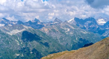 Dağ zirveleri bulutlu gökyüzüne karşı. Güneşli bir günde parlak bulutlu gökyüzüne uzanan muhteşem kayaların zirveleri.