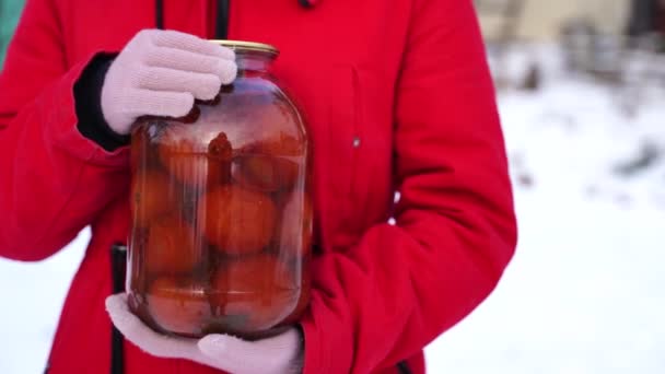 冬に庭で缶詰トマトを保持手袋で女性の手の閉じる 冬に漬け野菜の封印瓶を持っている正体不明の女性 — ストック動画