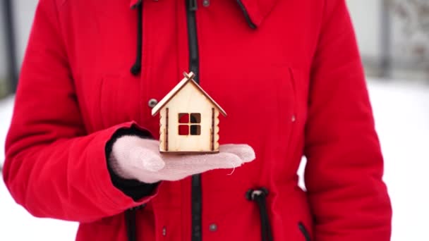 冬に小さな木造の家を保持手袋で一人の女性の手の閉じる 新しいアパートの購入の概念 — ストック動画