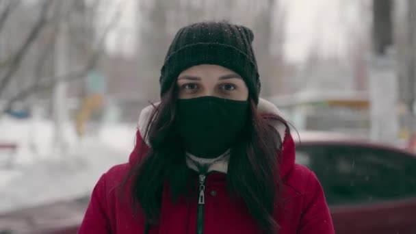 Kobieta Masce Medycznej Zimowych Ciuchach Stoi Zimą Zewnątrz Patrzy Kamerę — Wideo stockowe