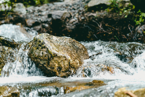 Close up of rapid clean stream flowing on rocks. Mountain river flows down and splashes
