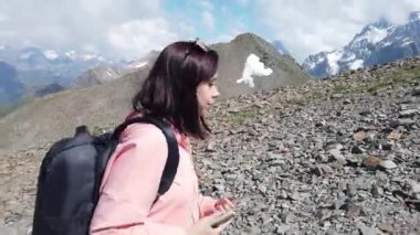 Dağlık arazide yürüyen genç bir kadına yakın durun. Güneşli bir günde sırt çantalı kadın turistin dağlık araziye gidişinin yan görüntüsü..