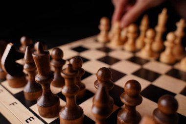 Gemideki siyah satranç taşlarını kapatın. Siyah arka planda satranç tahtasında iki sıra tahta figür. Akıllı, mantıklı ve stratejik oyun kavramı.