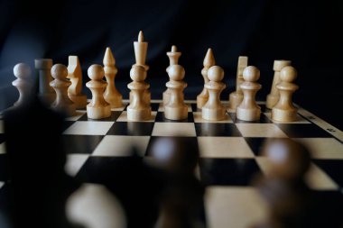 Siyah arka planda satranca yakın çekim. Tahta satranç taşları. Kavram: Masa oyunu ve entellektüel faaliyetler.