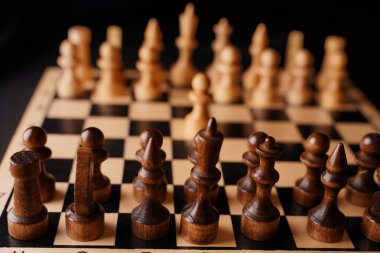 Gemideki beyaz ve siyah satranç taşlarını kapatın. Satranç tahtasındaki beyaz piyonun ilk hamlesine odaklan. Akıllı, mantıklı ve stratejik oyun kavramı