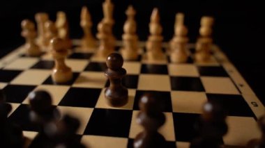 Satranç tahtasındaki beyaz ve siyah tahta parçaları. Siyah arkaplanda bir oyun sırasında kurulmuş bir satranç tahtası