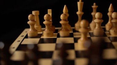 Siyah arka planda satranca yakın çekim. Tahta satranç taşları. Kavram: Masa oyunu ve entellektüel faaliyetler