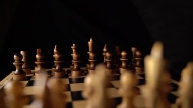 Siyah arka planda satranca yakın çekim. Tahta satranç taşları. Kavram: Masa oyunu ve entellektüel faaliyetler