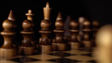 Siyah arka planda satranca yakın çekim. Tahta satranç taşları. Kavram: Masa oyunu ve entellektüel faaliyetler
