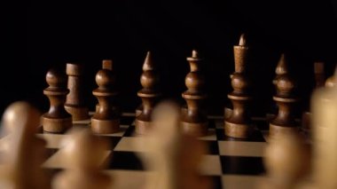 Siyah arka planda satranca yakın çekim. Tahta satranç taşları. Kavram: Masa oyunu ve entellektüel faaliyetler