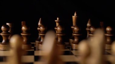 Siyah arka planda satranca yakın çekim. Tahta satranç taşları. Kavram: Masa oyunu ve entellektüel faaliyetler