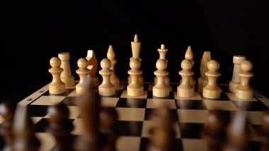 Siyah arka planda satranca yakın çekim. Tahta satranç taşları. Kavram: Masa oyunu ve entellektüel faaliyetler