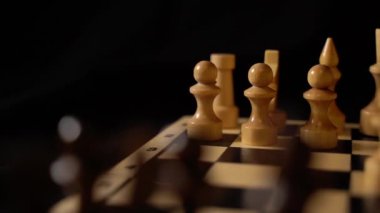 Satranç tahtasındaki beyaz ve siyah tahta parçaları. Siyah arkaplanda bir oyun sırasında kurulmuş bir satranç tahtası