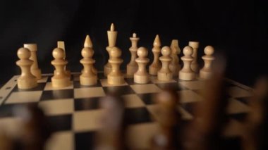 Gemideki beyaz satranç taşlarını buharla kaplayın. Siyah arka planda satranç tahtasında iki sıra tahta figür. Akıllı, mantıklı ve stratejik oyun kavramı