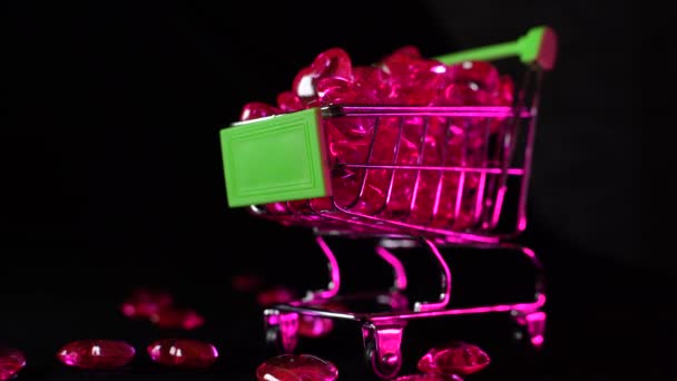 ショッピングカートの赤いハートの形 黒を背景に赤いハートでいっぱいの小さなスーパーマーケットのカート スーパーマーケットでの買い物 慈善の概念 — ストック動画