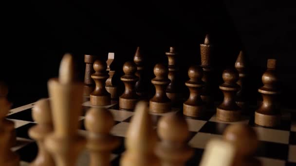 Зблизька шахи на чорному тлі. Дерев'яні шахові фігури. Концепція: настільна гра та інтелектуальна діяльність. — стокове відео