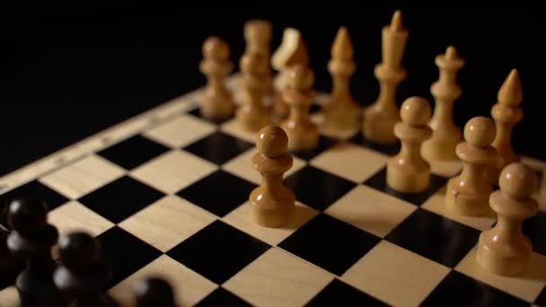 チェスボード上の白と黒の木製の作品 黒の背景にゲーム中に設定されたチェス盤 — ストック動画