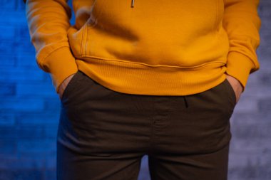 Metnin için kopyalanmış tuğla bir duvara karşı genç bir kadının vücudunun ön yüzü. Tanınmayan bir kadının elini pantolonunun cebine koy.