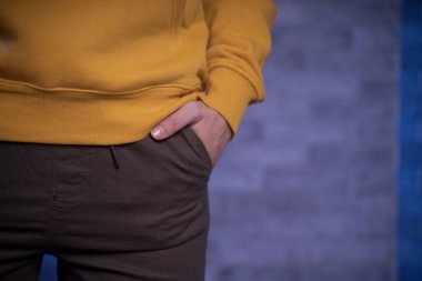 Metnin için kopyalanmış tuğla bir duvara karşı genç bir kadının vücudunun ön yüzü. Tanınmayan bir kadının elini pantolonunun cebine koy.